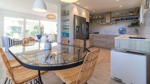 Une cuisine moderne avec une table à manger en verre, des chaises en osier et des appareils électroménagers intégrés.