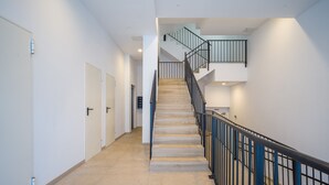 Un interior moderno con una escalera, paredes blancas y piso de baldosas.
