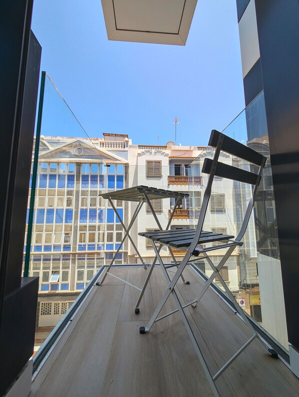 A balcony with a metal folding chair and a glass railing.