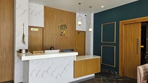 A reception desk with a wooden panel wall, a marble-patterned wall, and a dark blue accent wall.