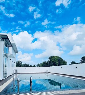 A modern pool with clear blue water, surrounded by a white wall and a clear sky. - Prosland Hotel (Tirur)