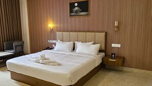 A neatly made bed with white linens and a towel, a bedside table with a phone, and a wall-mounted picture of a tree under a moon.
