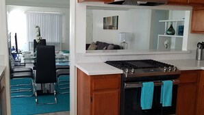 A kitchen with wooden cabinets, a stainless steel stove, and a blue towel hanging on the oven handle.