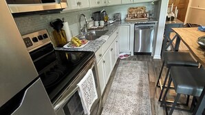 Una cocina moderna con armarios blancos, electrodomésticos de acero inoxidable y suelo de madera.