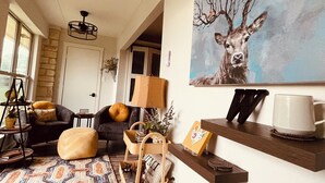 Un salón acogedor con un cuadro grande de un ciervo, una mesa de centro de madera y una alfombra estampada.