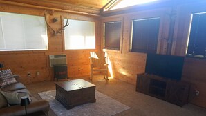 A cozy cabin interior with a fireplace, a television, a sofa, and a wooden ceiling. - Cozy Middle Fork Cabin.                      
    Across from Clearwater River  (Kamiah)