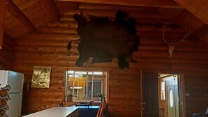 A log cabin interior with a dining area, a mounted animal head, and a window with blinds. - Cozy Middle Fork Cabin.                      
    Across from Clearwater River  (Kamiah)