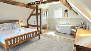 A bedroom with a wooden ceiling, a large bed, a bedside table, and a nightstand.