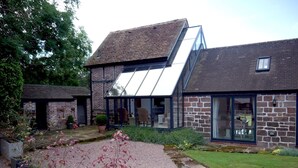 A modern house with a sloped roof, large glass windows, and a gravel driveway.