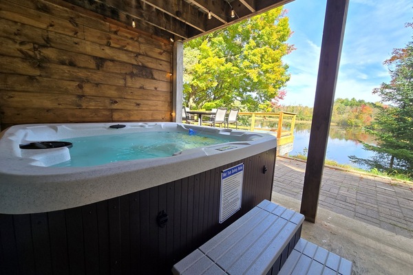 Unwind in our covered lakeside hot tub with stunning views! ✨ Enjoy bubbling water, peaceful nature, and vibrant trees—perfect for sunrise coffee or a relaxing sunset soak. 🌲🌅
