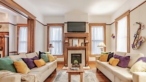 A living room with two sofas, a coffee table, a fireplace, and a television. - Central Location Historic Grandeur (Mobile)