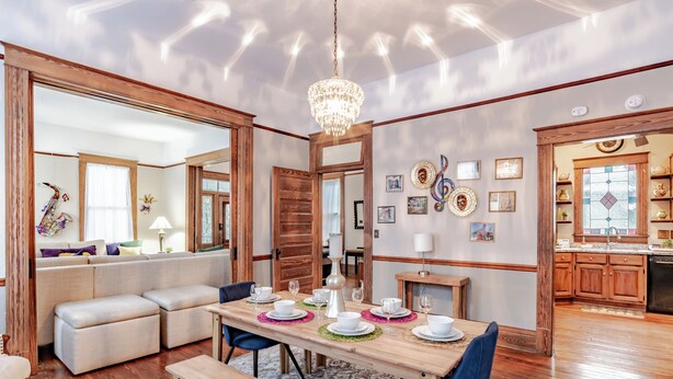 A dining area with a wooden table set for four, surrounded by blue chairs, and a bench. - Central Location Historic Grandeur (Mobile)