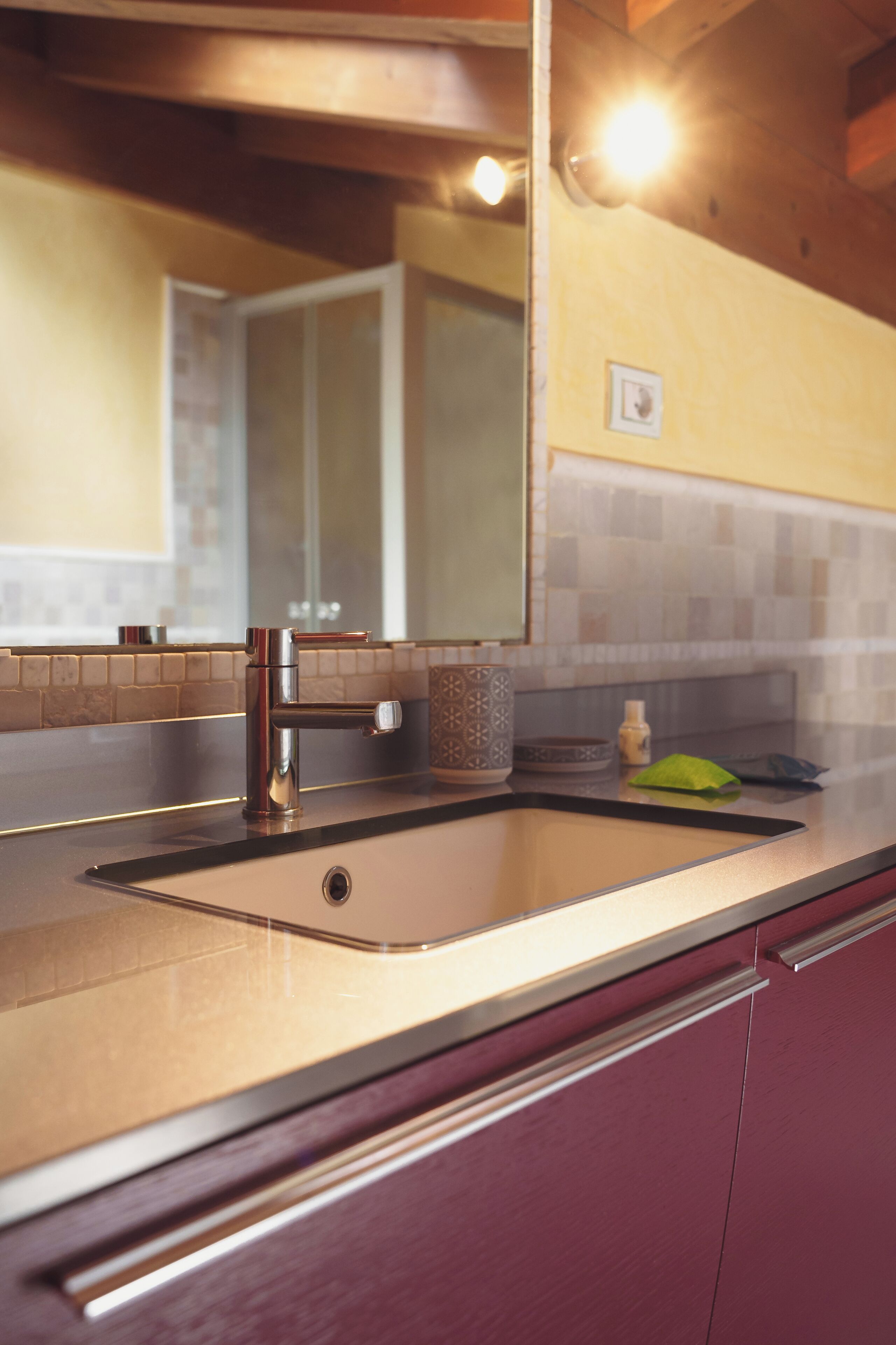 Una cocina con un lavamanos, un espejo y un salpicadero de azulejos.