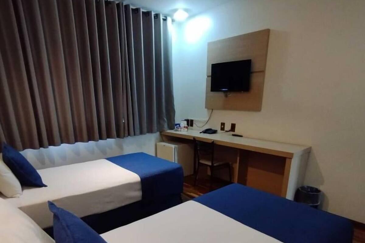 Habitación de hotel con dos camas, un escritorio, un televisor y una pequeña kitchenette.