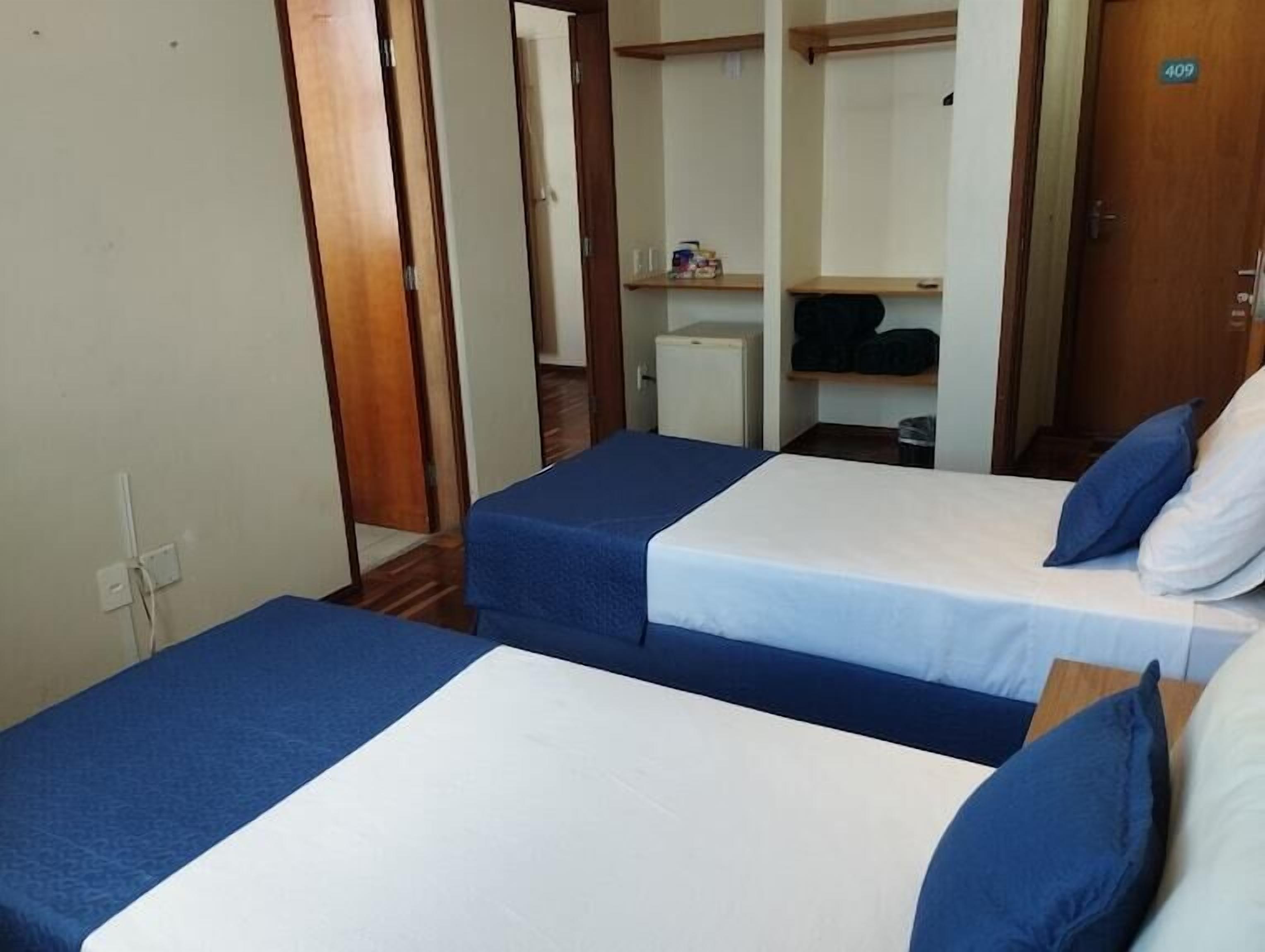 Una habitación con dos camas individuales, un escritorio pequeño y un armario.