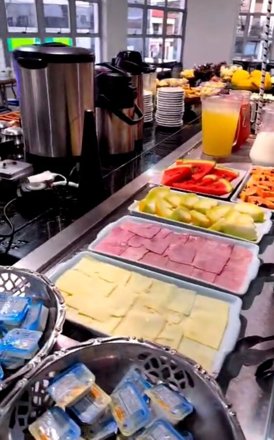 A buffet with various food options including fruits, meats, and beverages.