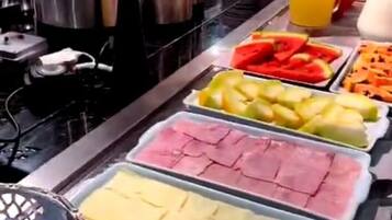 A buffet with various food options including fruits, meats, and beverages.