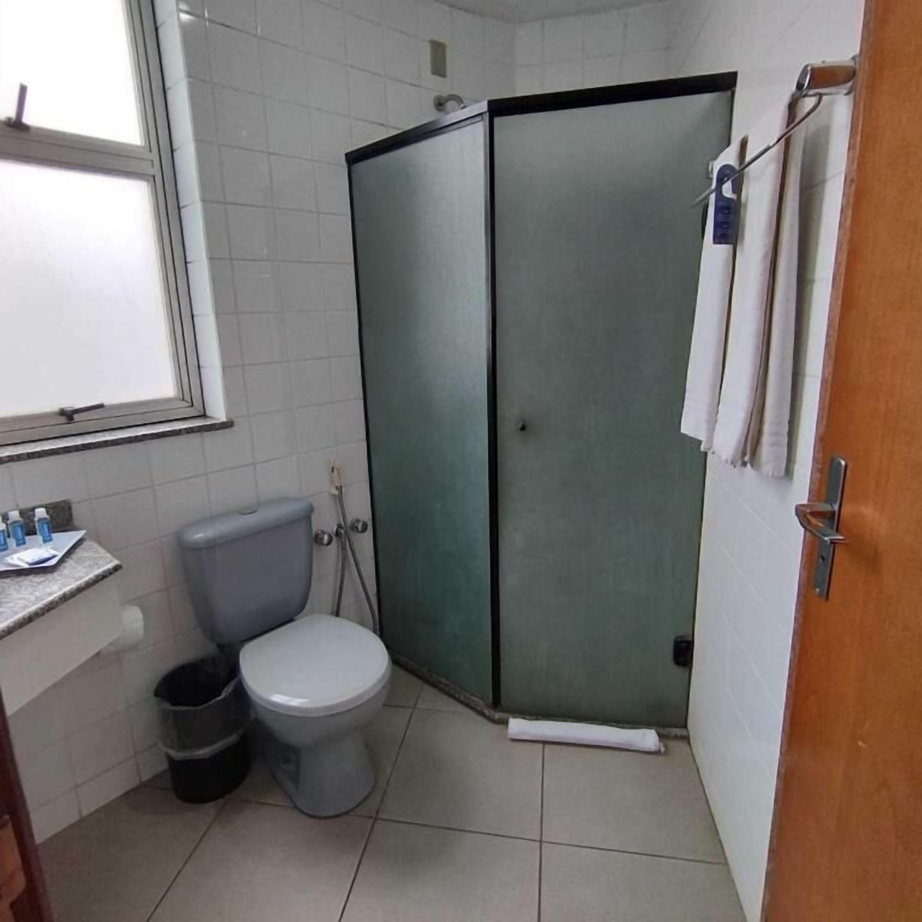 Un baño pequeño con inodoro, cabina de ducha y lavamanos.