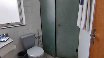 Un baño pequeño con inodoro, cabina de ducha y lavamanos.