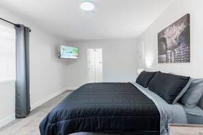A bedroom with a bed, a television, and a door. - 5Mins to Fremont! 10Mins to Strip! Sleeps 8! (Las Vegas)
