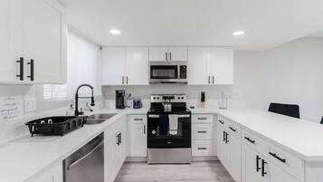 Una cocina moderna con armarios blancos, electrodomésticos de acero inoxidable y encimera de madera.