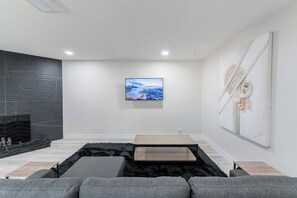 Una sala de estar moderna con chimenea, un televisor de pantalla plana montado en la pared y un cuadro abstracto de gran tamaño.