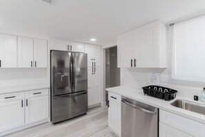 Una cocina moderna con armarios blancos, electrodomésticos de acero inoxidable y un lavavajillas integrado.