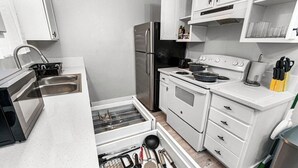 A compact kitchen with white cabinets, a stainless steel refrigerator, a stove, and a sink. - Cozy 1 Bed, Sleeps 4! Near Strip! Perfect GetAway! (Las Vegas)