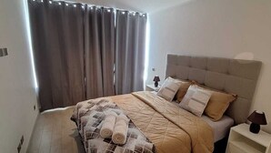 A bedroom with a bed, a nightstand, a lamp, and a window with curtains. - Nice and comfortable apartment in San Diego 376, Santiago (Santiago)
