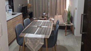 A modern kitchen with a dining area, featuring a table with chairs, a sofa, and a small side table with a plant. - Nice and comfortable apartment in San Diego 376, Santiago (Santiago)