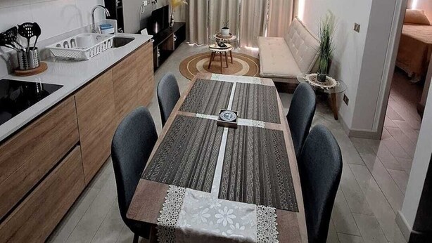 A modern kitchen with dark cabinets, a white countertop, and a dining area with a patterned tablecloth. - Nice and comfortable apartment in San Diego 376, Santiago (Santiago)