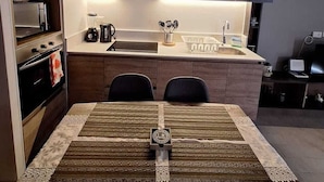 A modern kitchen with dark cabinetry, a central island, and a dining area with a table set for two. - Nice and comfortable apartment in San Diego 376, Santiago (Santiago)