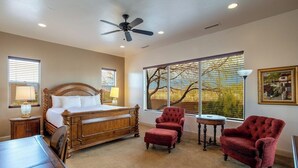 A bedroom with a wooden bed, a red armchair, a small table, and a window with a view of trees. - Courtyard: Golf + Resort Access + Sand Dunes (Hurricane)