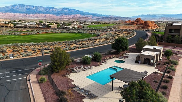 A pool area with a view of mountains, a golf course, and a road with a stop sign.