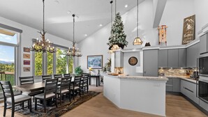 A modern kitchen with a central island, grey cabinetry, and a dining area with a large table and chairs. - L1726-5 (Keystone)