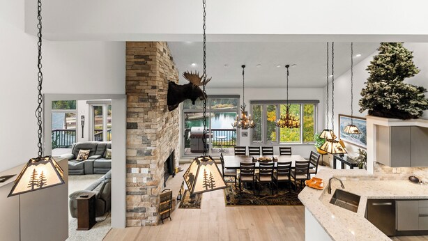 A spacious living area with a fireplace, a dining table, and a view of a lake. - L1726-5 (Keystone)