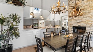 A modern kitchen with a central island, pendant lighting, and a stone fireplace. - L1726-5 (Keystone)