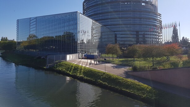Ein modernes Gebäude mit Glasfassade, einer gewölbten Struktur und einer Fahnenmast mit mehreren Flaggen.