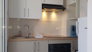 Eine moderne Küche mit weißen Schränken, einem schwarzen Backofen und einer Kaffeemaschine.