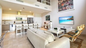 Een ruime woonkamer met een hoge plafond, een keuken met moderne apparatuur, een eethoek en een groot raam met uitzicht.