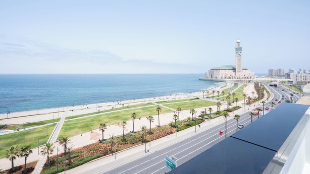 A coastal cityscape with a prominent mosque, a wide promenade, and a busy road. - Atlantic View Appart'Hotel (Casablanca)