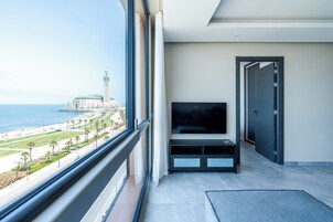 Habitación de hotel moderna con un ventanal grande que ofrece vistas a una playa y una mezquita.