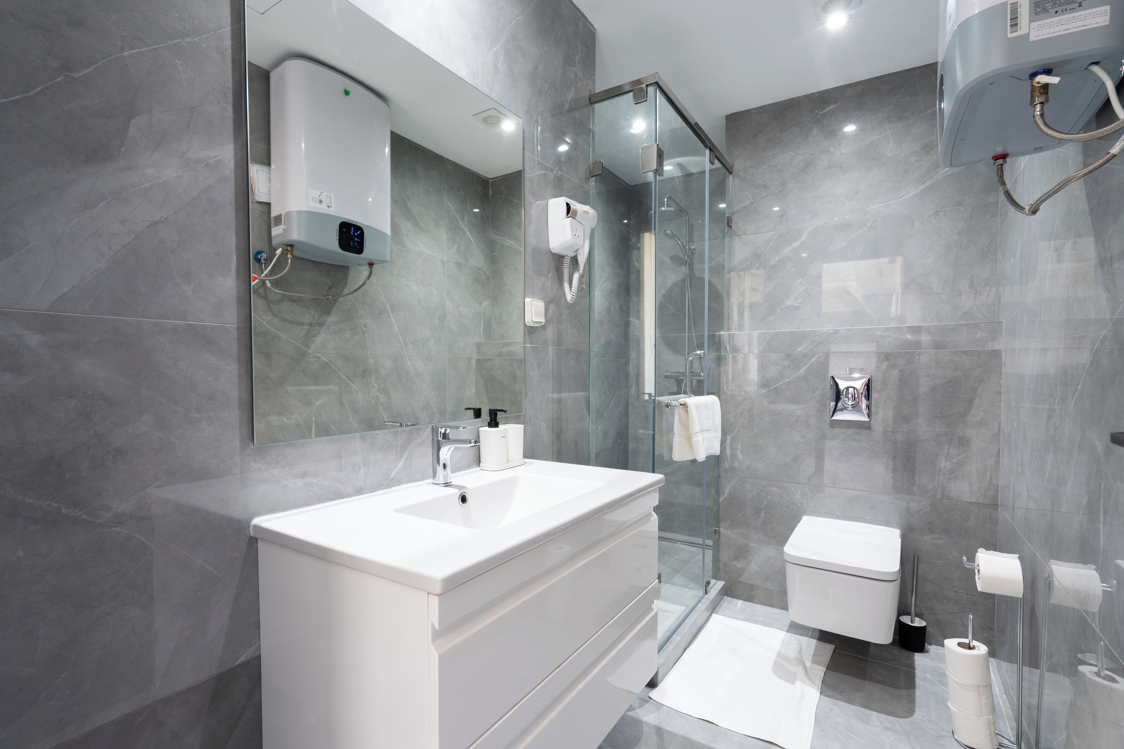 A modern bathroom with a glass-enclosed shower, a white sink, and a toilet.