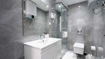 Une salle de bain moderne avec une douche à parois de verre, un lavabo blanc et des toilettes.