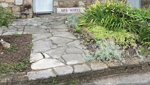 A stone building with a metal roof, two white doors, and a sign reading "FOX MOTEL".