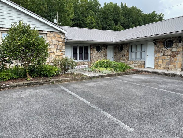 A motel with stone exterior walls, a covered parking area, and a sign reading "FOX MOTEI".