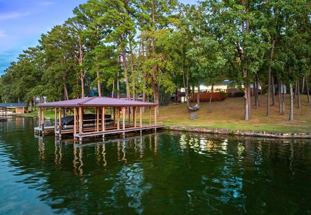 Un chalet au bord du lac, doté d’un quai, entouré d’arbres et d’une zone herbeuse.