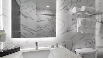 A modern bathroom with a marble sink, a toilet, and a towel rack with towels.