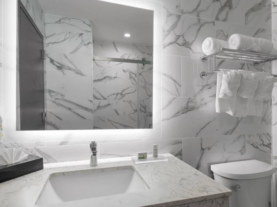 A modern bathroom with a marble sink, a toilet, and a towel rack with towels.