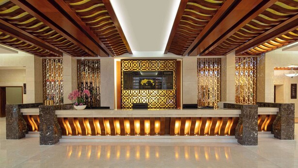Un área de recepción con diseño moderno, que incluye un mostrador de recepción, paneles decorativos y un techo con vigas de madera.